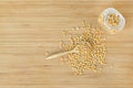 Whole grain soybeans in bottle and spoon on bamboo wooden board, top view