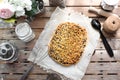 Whole grated pie on a sheet of parchment paper surrounded by kitchen utensils on a wooden table top view