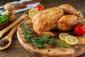 Whole grilled chicken with caramelized skin and fresh rosemary on a wooden dinner table