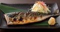 Grilled Mackerel Fish Served on a Black Plate with Shredded Salad and Grated Daikon Radish Royalty Free Stock Photo