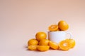 Whole and half cut fresh oranges with white ceramic mug on soft cream background Royalty Free Stock Photo