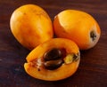 Whole and half fresh yellow loquat on wooden table