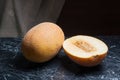 Whole and half honeydew melon fruit on dark marble background. Royalty Free Stock Photo