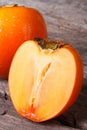 Whole and half persimmon closeup on a wooden table.