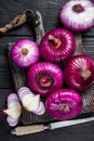 Whole and halfed Flat red sweet onion on a cutting board. Black Wooden background. Top View