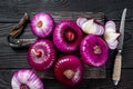 Whole and halfed Flat red sweet onion on a cutting board. Black Wooden background. Top View