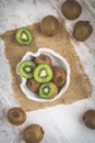 Whole and halfed kiwis in a bowl and on a white wooden table