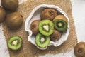 Whole and halfed kiwis in a bowl and on a white wooden table