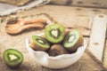 Whole and halfed kiwis in a white bowl on a rustic wooden table