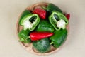 Whole and halved bell peppers on wooden dish, top view
