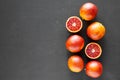 Whole and halved blood oranges on black background, top view. Flat lay, overhead, from above. Copy space Royalty Free Stock Photo