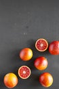 Whole and halved blood oranges on black table, top view. Flat lay, overhead, from above. Copy space Royalty Free Stock Photo