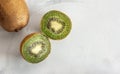 Whole and Halved Kiwi Fruits on a Gray White Surface