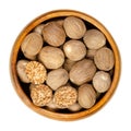 Whole and halved nutmegs, dried seeds, in a wooden bowl