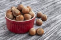Whole hazelnuts in red bowl. Filbert nuts on black wooden table. Royalty Free Stock Photo
