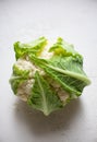 Whole head of the fresh raw cauliflower with leaves on a white textured background. Clean eating and heathy diet concept. Royalty Free Stock Photo