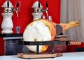 Whole italian leg raw ham with its cutting board on the table of a bar. Beer dispensing system on background