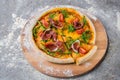 Pizza jamon slices, cherry tomatoes served with fresh arugula leaves on top on wooden plate served with flour and spices