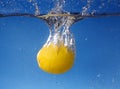 Whole lemon dropped in water against gradient blue