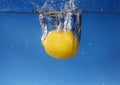 Whole lemon dropped in water against gradient