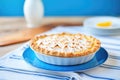 whole lemon meringue pie on white plate, blue tablecloth background Royalty Free Stock Photo