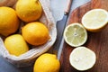 Whole lemons next to cut ones on a wooden board next to a knife Royalty Free Stock Photo