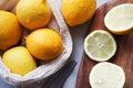 Whole lemons next to cut ones on a wooden board next to a knife Royalty Free Stock Photo