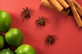 Whole limes and cinnamon sticks on red background.