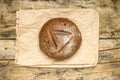 Whole loaf of bread with paper bag on weathered wood background