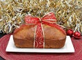 Whole loaf cake wrapped in a red and gold ribbon.