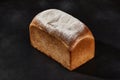 Whole loaf of fresh, delicious baked white bread sprinkled with flour. Black background with copy space. Close-up