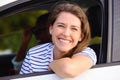 A whole lot of fun up ahead. Portrait of a young woman looking out of a car window during a road trip with her husband. Royalty Free Stock Photo