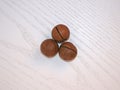 Whole macadamia nuts on a light wooden background. Macadamia nuts close-up. As many as three round macadamia nuts on a wooden surf