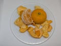 Whole and Peeled Mandarin Oranges with Peels Spread on a White Plate Royalty Free Stock Photo