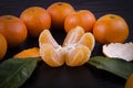 Whole mature tangerines around green leaflets and tangerine particles