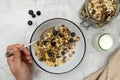 Whole oats breakfast, granola with dried fruit and blueberry, milk and honey. Hand holding the spoon. Copy space Royalty Free Stock Photo