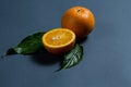 A whole orange and half an orange, and two green leaves Royalty Free Stock Photo