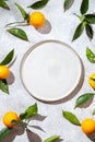Whole oranges witl orange tree leaves on white background around empty plate. top view, flat lay, summer and healthy Royalty Free Stock Photo
