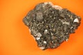 Whole piece of black lead ore block formation with irregular texture, shot on orange paper background Royalty Free Stock Photo