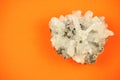 Whole piece of white quartz crystal formation with irregular texture, shot on orange paper background