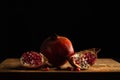 Whole pomegranate and two quarters of a pomegranate on a wooden board Royalty Free Stock Photo