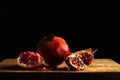 Whole pomegranate and two quarters of a pomegranate on a wooden board Royalty Free Stock Photo