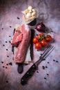 Whole pork tenderloin meat on vintage board with garlic and tomatoes Royalty Free Stock Photo