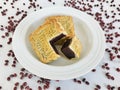 A whole and a quarter-cut mooncakes in a white round plate on white marble background with rd beans surrounding. Royalty Free Stock Photo