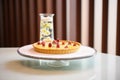 whole raspberry tart on a glass stand with a pastry server