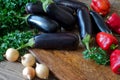 Whole raw eggplant, onions, red bell pepper and parsley on wooden cutting board Royalty Free Stock Photo