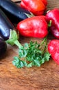 Whole raw eggplant, onions, red bell pepper and parsley on wooden cutting board Royalty Free Stock Photo