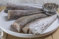 Whole raw hake fish portions arranged on white plate with spices on kitchen table Royalty Free Stock Photo