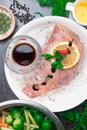 Whole raw organic fish sea perch on ice cubes in white plate on a dark table background with black pepper, olive oil, dill, cilant Royalty Free Stock Photo