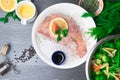 Whole raw organic fish sea perch on ice cubes in white plate on a dark table background with black pepper, olive oil, dill, cilant Royalty Free Stock Photo